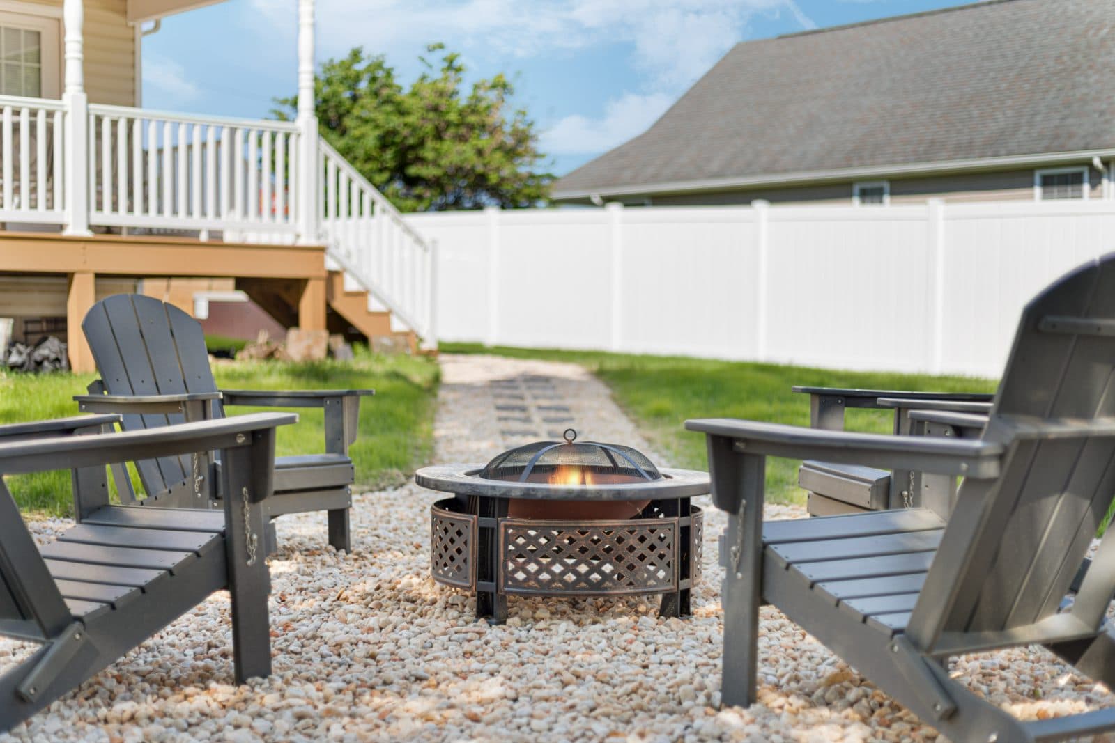 Fire pit with Adirondack chairs in the fenced backyard at Heart of Luray
